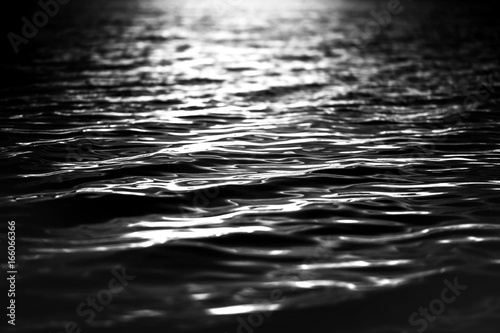 Rippled water surface at night. Light on the water from a lighthouse or rescue boat (lifeboat). Spotlight on the water. Background