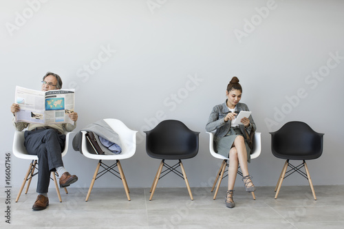 Man reading newspaper and woman using digital tablet