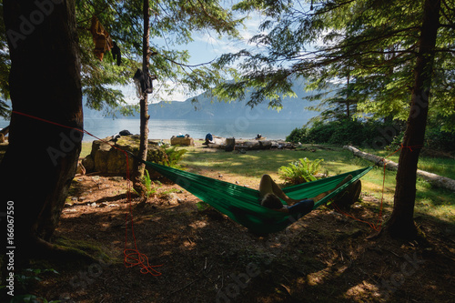 Man in hammock under trees on beach near lake