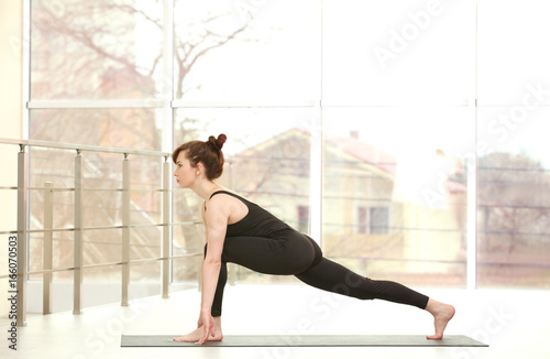 Young woman practicing yoga against window