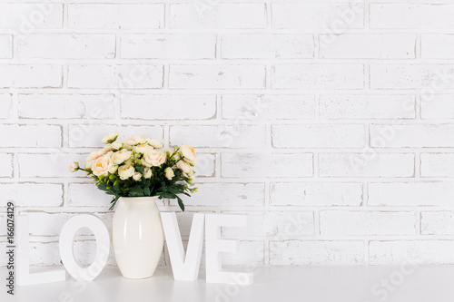 summer background - rose flowers and wooden word love over brick wall