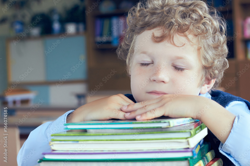 Tired blond curly boy on a pile of books Tired blond curly boy on a pile of books