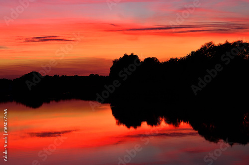 Fototapeta Naklejka Na Ścianę i Meble -  Zachód słońca nad jeziorem i odbicie w wodzie