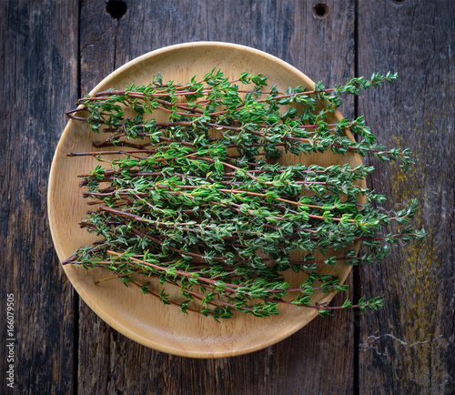 Thyme herb in woodplate on wooden table photo