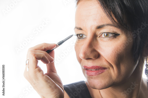 Mature caucasian woman applying mascara on her eyelids