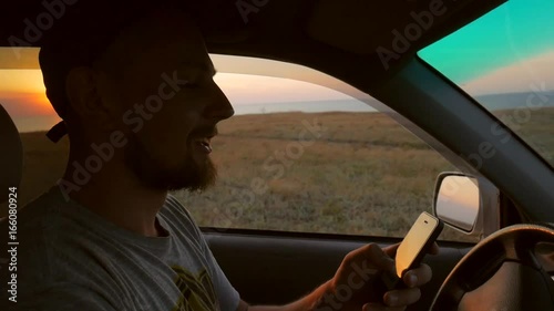 Wallpaper Mural Young Bearded Man Driving Car and Watching Navigation Map on Smart Phone. Travel HD Slowmotion Lifestyle Footage. Torontodigital.ca