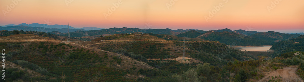 Evening panorama of a countryside between Tirana and Durres, Albania. Hills and forests captured during scenic sunset with orange sky and mist. 