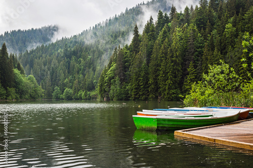 Mountain lake scenery, Lacu Rosu or Red lake with boats near the shore, Eastern Carpathians, Romania, nature landscape background