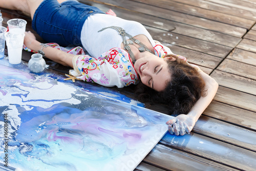 Foto Young beautiful artist woman is painting with acrylic paint on open air session