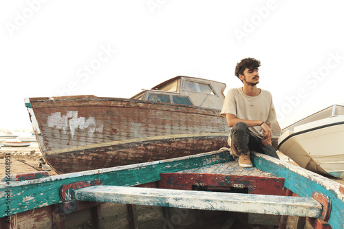 Young man on a beach with boats