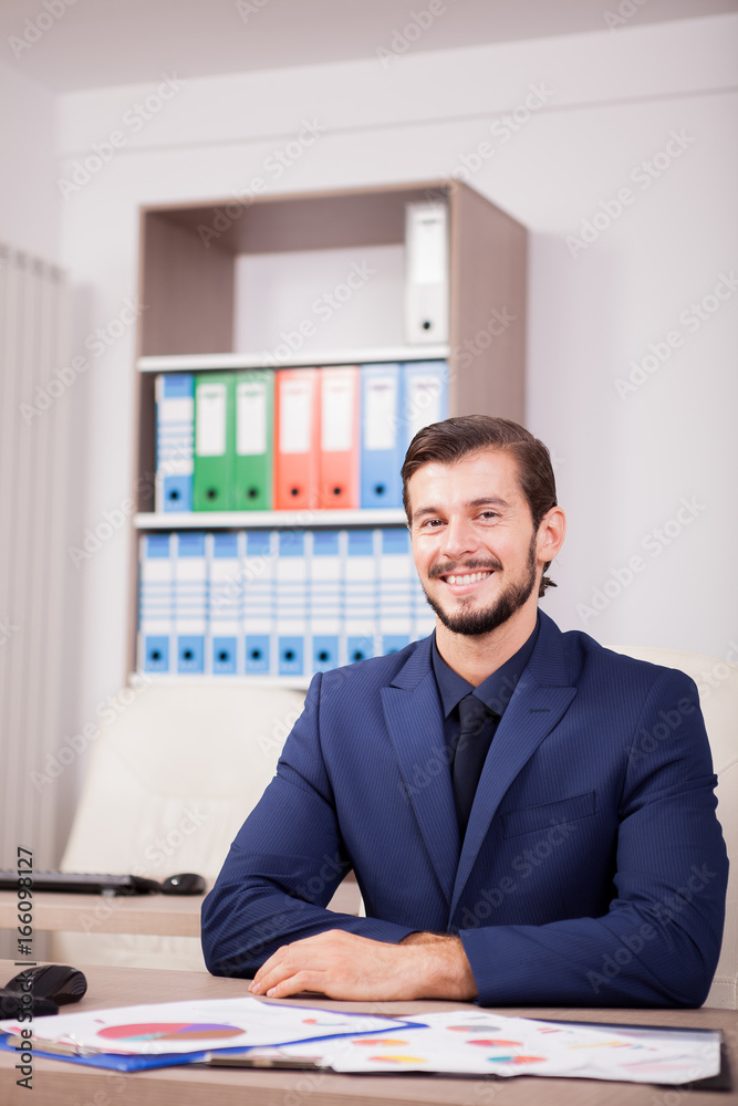 Smiling happy entrepreneur in business suit at his work place. Image of succesful positive businessman at his new modern office Smiling happy entrepreneur in business suit at his work place. Image of succesful positive businessman at his new modern office