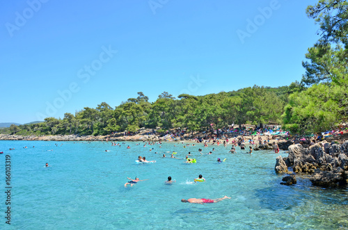People are swimming in a turquoise sea in Incekum Beach, Marmaris.