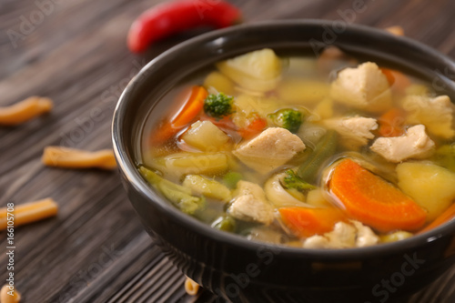 Bowl with delicious turkey soup on wooden background