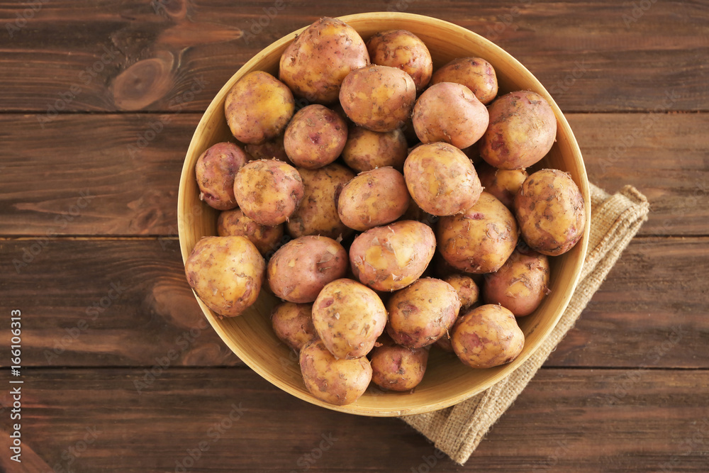Bowl with raw organic potato on wooden table Bowl with raw organic potato on wooden table