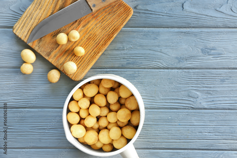 Saucepan with raw organic potato on wooden table Saucepan with raw organic potato on wooden table