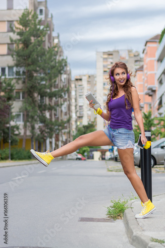 Image of young happy woman, listening music and having fun on the street. Lifestyle. Outdoor. © zeljkomatic76