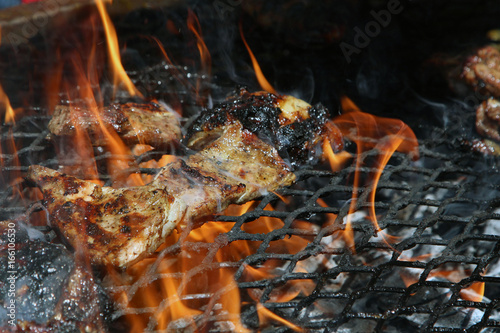 Close up of delicious whole lamb chop meat pieces on a grill under flames photo