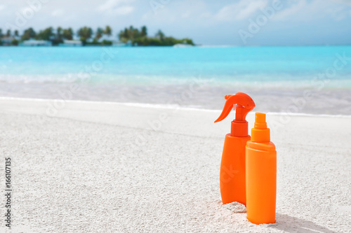 Bottles with sunscreen cream on sea beach. Summer vacation concept