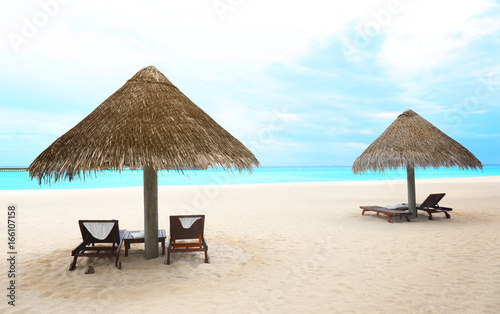 View of sea beach with sun loungers and umbrellas on summer day © Africa Studio