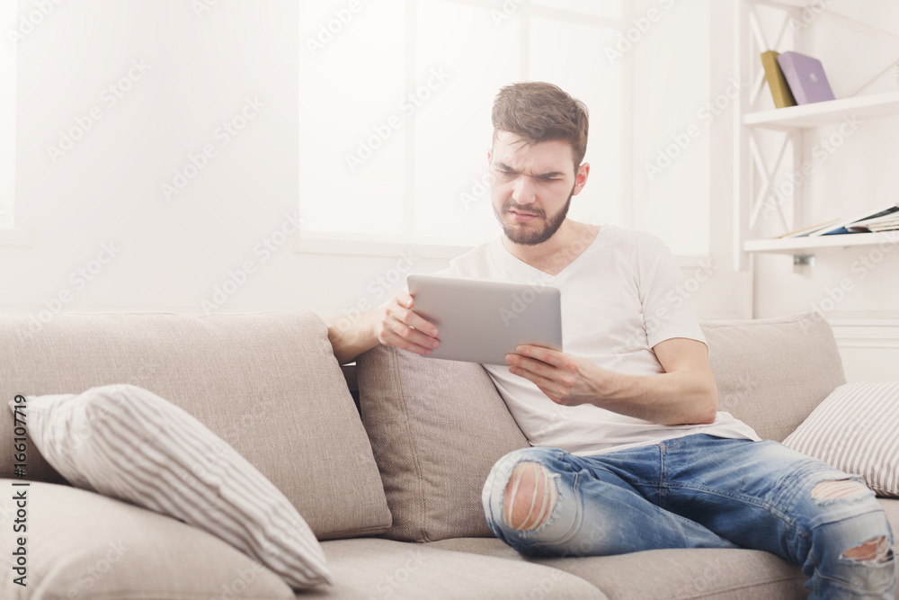 Young man at home reading on tablet Young man at home reading on tablet
