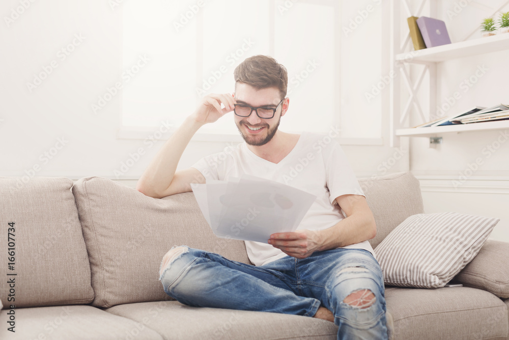 Happy young businessman reading paperwork at home Happy young businessman reading paperwork at home