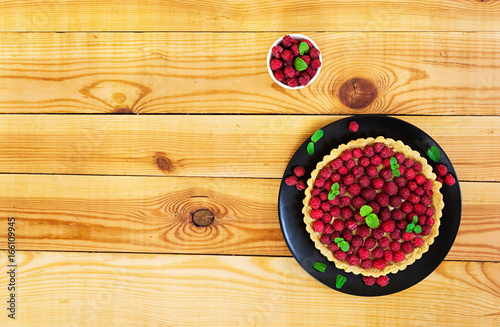 Delicious tart with custard and raspberry on wooden background