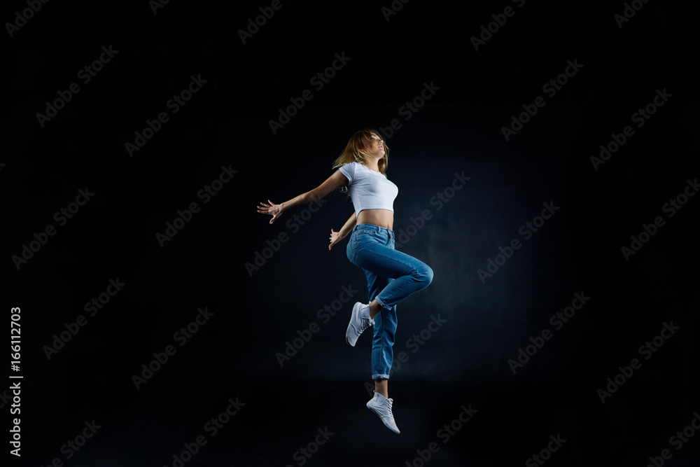 Studio shot of beautiful young European woman dancer with slim flexible body practising indoors, sharpening her dancing skills, dressed in sensible clothing. People, hobby and active lifestyle concept