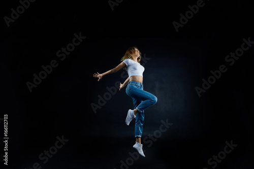 Studio shot of beautiful young European woman dancer with slim flexible body practising indoors, sharpening her dancing skills, dressed in sensible clothing. People, hobby and active lifestyle concept