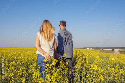 Couple is walking through a field of yellow flowers