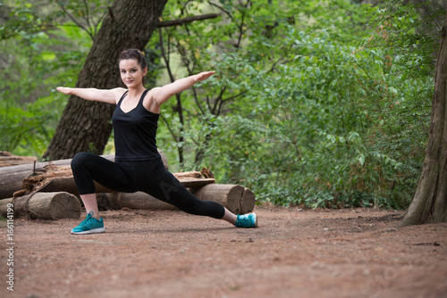 Fitness Woman Stretching In Wooded Forest Area