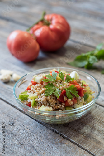 Bowl of fresh organic quinoa salad on wooden table. Shallow depth of field.