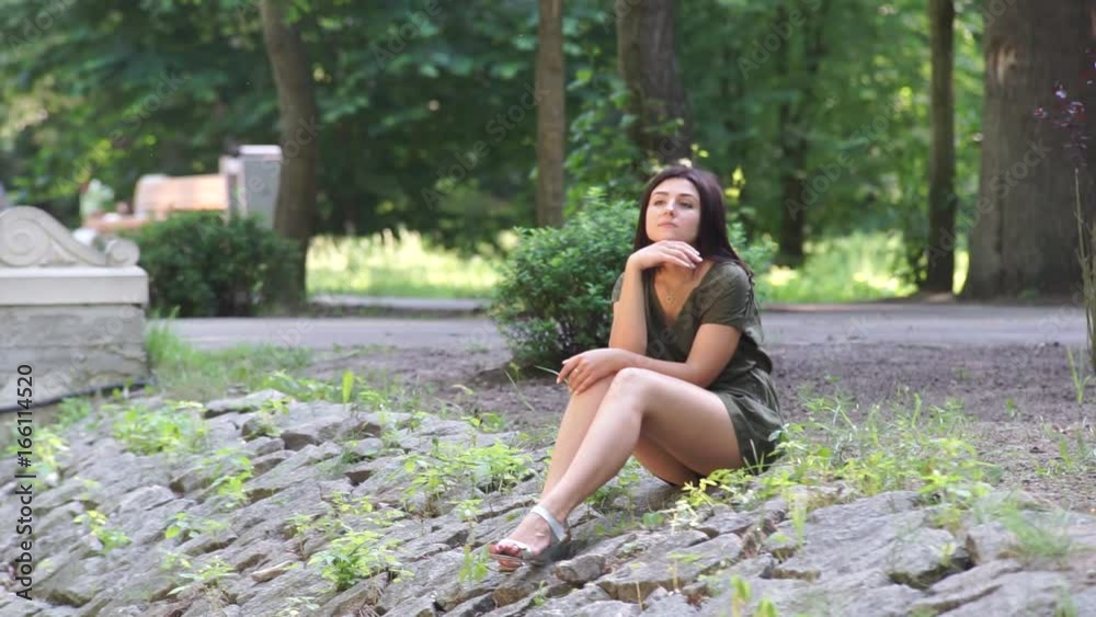 A girl sits on rocks in a recreation parkc A girl sits on the rocks in a recreation park. She admires the fact that it takes place on her. Looks around A girl sits on rocks in a recreation parkc A girl sits on the rocks in a recreation park. She admires the fact that it takes place on her. Looks around