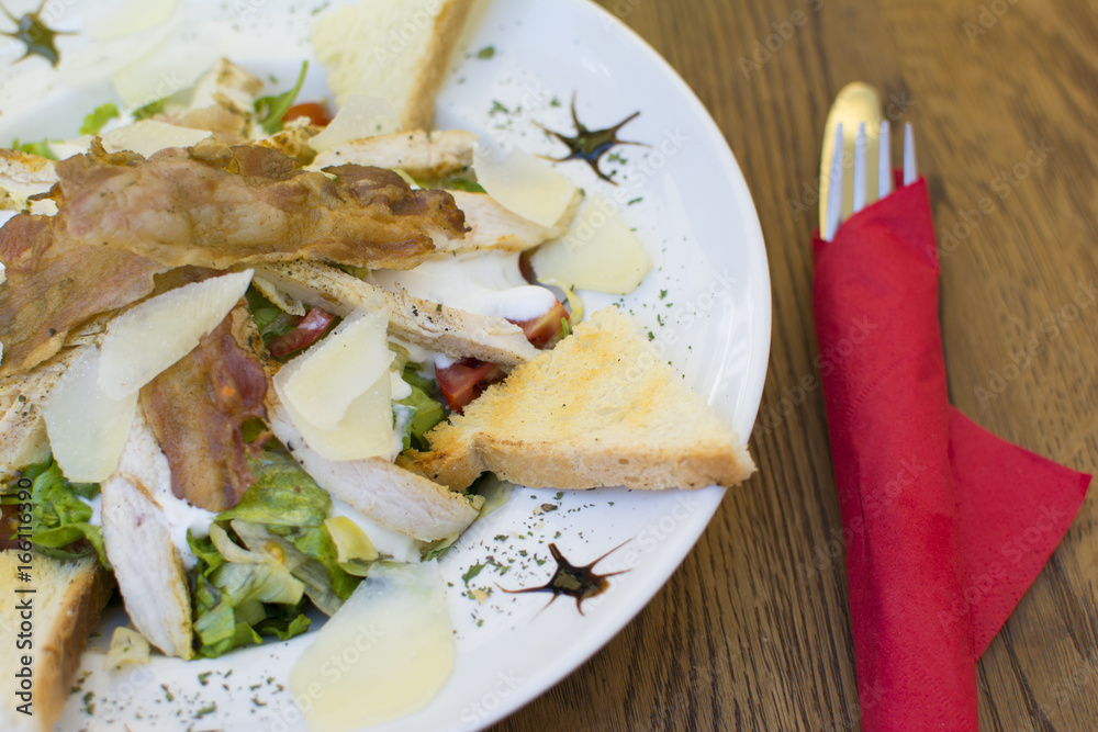 Delicious caesar salad with cheese on a rustic wooden table. Delicious meal in the restaurant on a sunny day. Delicious caesar salad with cheese on a rustic wooden table. Delicious meal in the restaurant on a sunny day.
