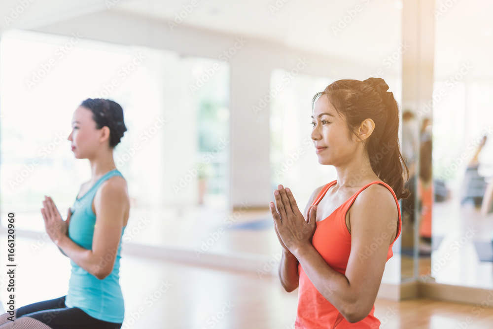 fitness, sport, training, yoga and people concept - Asian woman do exercise in gym.Group Of female Doing Yoga Indoors