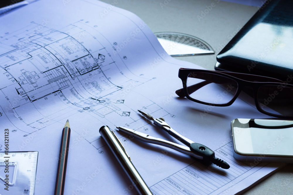 Divider, pencil, pen, ruler, glasses and smartphone and blueprint on table top.Table top view of Engineers table at office workplace.selective focus. Divider, pencil, pen, ruler, glasses and smartphone and blueprint on table top.Table top view of Engineers table at office workplace.selective focus.