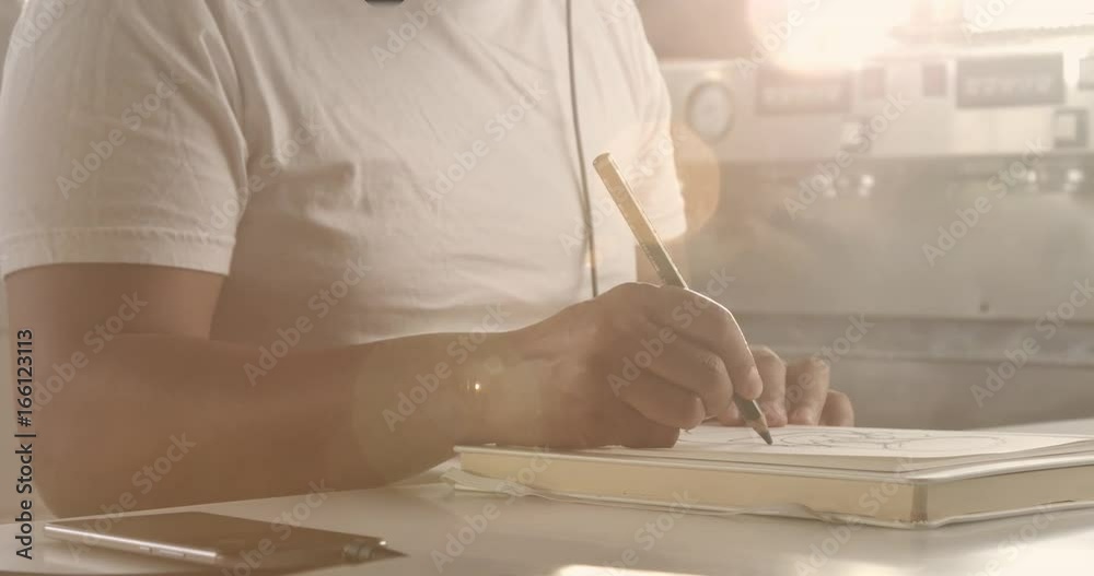 closeup of man's had drawing in notepad in caffee and than pan movement of camera to his portrait