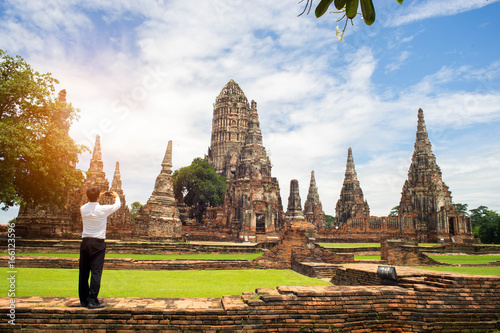 Businessman take a photo of ancient Buddha with smartphone .