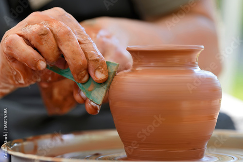 Fototapeta Potter making ceramic pot on the pottery wheel