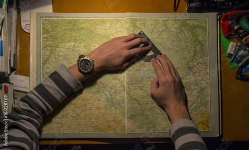 Canvas Print The cartographer works with the protractor on the map