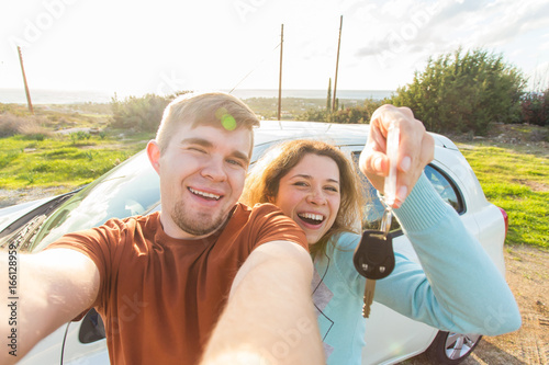 Young funny couple with keys to new car outdoor photo