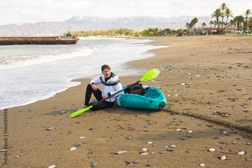 Man sitting on the beach with kayak. Traveling by sea. Leisure activities on the water. Man sitting on the beach with kayak. Traveling by sea. Leisure activities on the water.