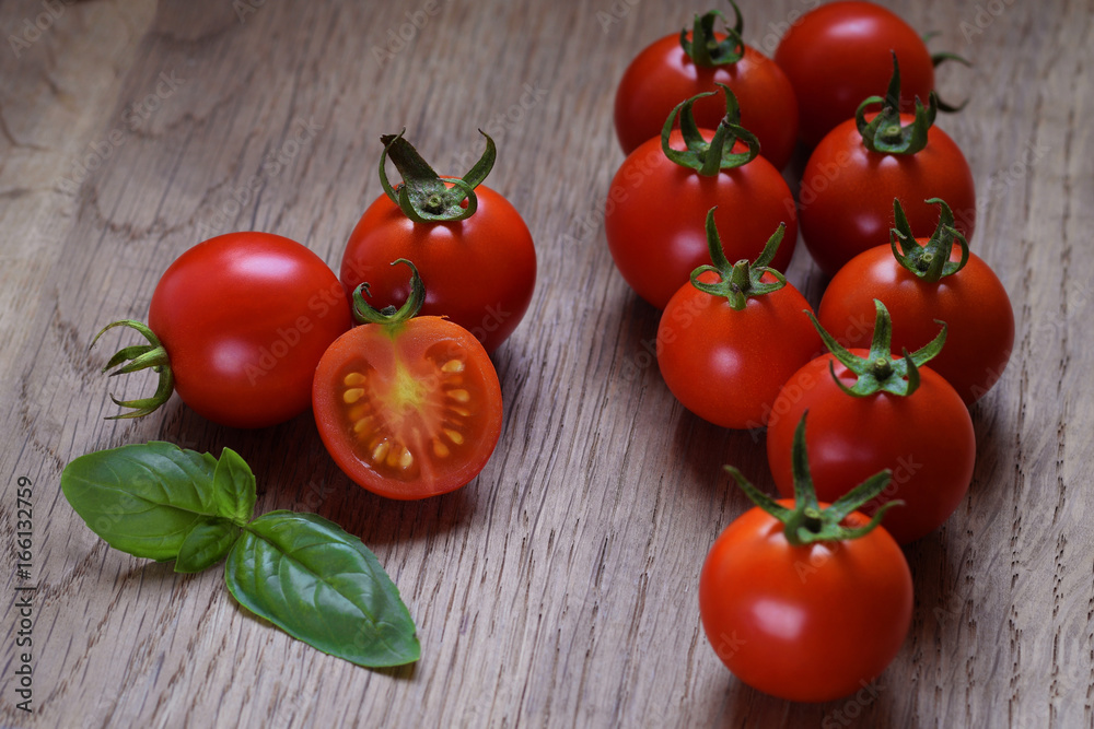 Red tomatoes with green basil leaves on wooden background Red tomatoes with green basil leaves on wooden background