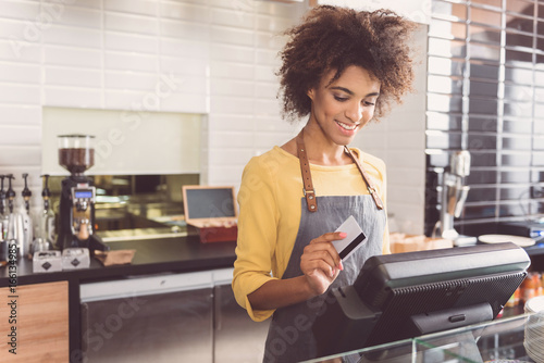 Cheerful young woman cashier is working in cafe photo