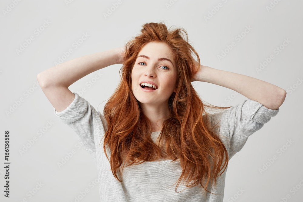 Portrait of happy young beautiful redhead girl smiling looking at camera touching hair over white background. Portrait of happy young beautiful redhead girl smiling looking at camera touching hair over white background.
