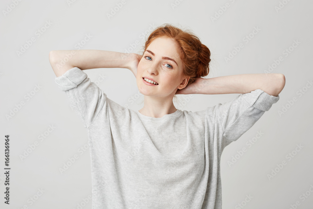 Portrait of young beautiful redhead girl with hands behind head smiling looking at camera over white background. Portrait of young beautiful redhead girl with hands behind head smiling looking at camera over white background.
