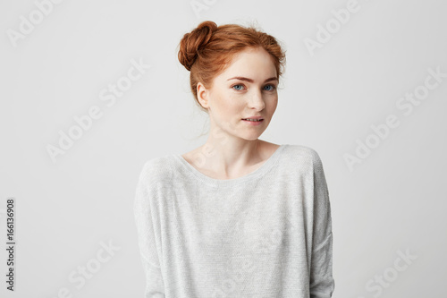 Portrait of young beautiful foxy girl with freckles looking at camera smiling over white background.