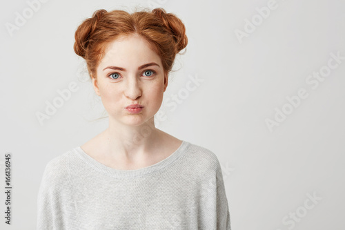 Portrait of young pretty ginger girl making funny face looking at camera over white background.