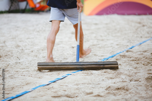 Obraz na plátně Man flatten sand surface at beach volleyball court.