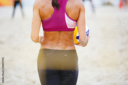 Volleyball player is a female athlete getting ready to serve the ball.