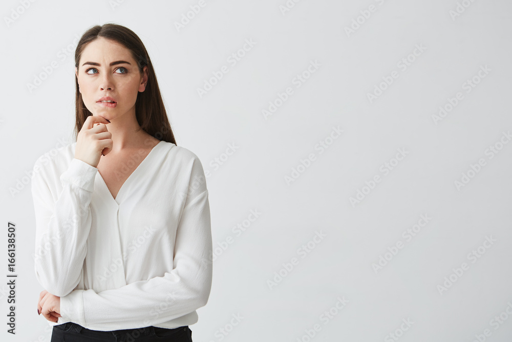 Portrait of young beautiful brunette businesswoman dreaming thinking frowning over white background. Hand on chin. Portrait of young beautiful brunette businesswoman dreaming thinking frowning over white background. Hand on chin.